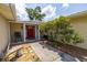 Inviting front porch with red door, lush landscaping, and a decorative bench at 1891 Harmony Dr, Clearwater, FL 33756