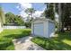 A detached garage with a driveway, set in a yard with green grass and some shade at 1891 Harmony Dr, Clearwater, FL 33756