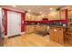 Well-lit kitchen with hardwood floors, wooden cabinets, black countertops, and red accent wall at 1891 Harmony Dr, Clearwater, FL 33756