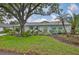 Charming home with a lush landscaped yard featuring a mature tree, green lawn, and garden bench at 1902 Hanson Ct # 308, Sun City Center, FL 33573
