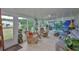 An enclosed sun room with large windows, ceiling fan, tile floor, and two floral print chairs with gray loveseat at 1902 Hanson Ct # 308, Sun City Center, FL 33573