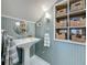 Quaint bathroom with pedestal sink, paneled walls, and decorative storage with wicker baskets at 231 15Th Ne Ave, St Petersburg, FL 33704