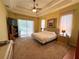 Relaxing main bedroom with carpet, tray ceilings, and outdoor access at 2349 Wood Pointe Dr, Holiday, FL 34691