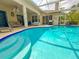 Covered lanai with large pool and spa, outdoor kitchen and lush foliage at 2349 Wood Pointe Dr, Holiday, FL 34691