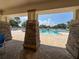 Picturesque view of the community pool from a shaded area with brick pillars at 2349 Wood Pointe Dr, Holiday, FL 34691
