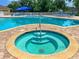 Inviting pool area features a relaxing spa surrounded by stone pavers and lounge chairs at 2349 Wood Pointe Dr, Holiday, FL 34691