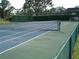 Well-maintained tennis court surrounded by green fencing and mature trees at 2980 Haines Bayshore Rd # 124, Clearwater, FL 33760