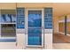 Close-up of the bright blue front door with a sidelight window and a covered carport entrance at 306 12Th Ave, Indian Rocks Beach, FL 33785