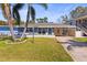 Inviting single-story home with a blue accent wall, lush lawn, and a convenient carport at 306 12Th Ave, Indian Rocks Beach, FL 33785