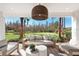 Comfortable covered patio featuring stylish outdoor seating, a modern light fixture and beautiful backyard views at 3198 Malta Ave, Wesley Chapel, FL 33543