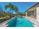 Backyard pool with outdoor seating, spa, statues, and lush landscaping under a clear blue sky at 32523 Neroli St, Wesley Chapel, FL 33543