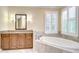 Bathroom featuring a soaking tub, vanity with granite countertop, and plantation shutters at 3323 Anna George Dr, Valrico, FL 33596