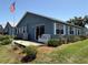 Back of home with sliding glass doors, landscaping, white bench, and an American flag at 37401 Teaberry Loop, Zephyrhills, FL 33542