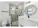 Modern bathroom featuring a glass shower, patterned tile, and a sleek vanity with a round mirror at 3817 W San Nicholas St, Tampa, FL 33629