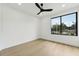 Modern bedroom with light wood flooring, black ceiling fan, and a large window with neighborhood views at 3817 W San Nicholas St, Tampa, FL 33629