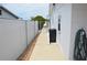 Sideyard next to house with fence, green hose, door, garbage bin, and newly poured cement walkway at 4922 Genesis Ave, Holiday, FL 34690