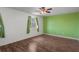 Bright bedroom features a ceiling fan, wood-look flooring, and large window with green curtains at 5144 Cedarbrook Ln, Hernando Beach, FL 34607