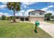 Charming two-story home with a lush green lawn, palm tree, and a two-car garage at 5144 Cedarbrook Ln, Hernando Beach, FL 34607