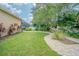 Large backyard with a well maintained lawn, brick walkway, and lush landscaping at 5317 Pagnotta Pl, Lutz, FL 33558
