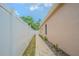Side view of the property with a long walkway between the house and a tall white fence at 5317 Pagnotta Pl, Lutz, FL 33558