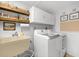 Bright laundry room with white cabinets, laundry sink, washer, and dryer, and shelving for storage at 535 Sandy Hook, Palm Harbor, FL 34683