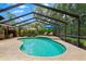 Private screened-in pool offers a refreshing escape with a beautifully tiled sun shelf and landscaping at 535 Sandy Hook, Palm Harbor, FL 34683