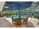 Relaxing pool area with a dining table, blue umbrella, and a screened enclosure for year-round enjoyment at 535 Sandy Hook, Palm Harbor, FL 34683
