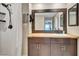 Bathroom featuring a white tiled shower, rustic vanity, and dark framed mirror at 7225 Ronnie Gardens Ct, Tampa, FL 33619