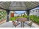 Cozy covered patio with a dining set, decorative privacy curtains, and green lawn views at 7225 Ronnie Gardens Ct, Tampa, FL 33619