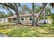 Landscaped front yard with mature trees framing a tan one-story home with white trim at 770 27Th S Ave, St Petersburg, FL 33705