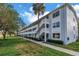 Well-maintained condo building with white exterior, staircase, and landscaped grounds under a sunny sky at 7801 11Th N St # 104, St Petersburg, FL 33702