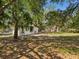 A view of the compact white home nestled within the trees with the house's backyard in the foreground at 7813 Cadillac Ave, Hudson, FL 34667