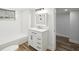 This bathroom features white cabinets, a vanity, shower-tub, and wood-look flooring at 7813 Cadillac Ave, Hudson, FL 34667