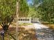 Cozy home with a covered carport and mailbox, framed by lush trees and a concrete driveway at 7813 Cadillac Ave, Hudson, FL 34667