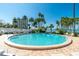 Community swimming pool with lounge chairs surrounded by palm trees and a partial view of the water at 80 Rogers St # 6D, Clearwater, FL 33756