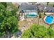 Aerial view of a spacious backyard with a screened pool, surrounded by mature trees and a privacy fence at 8737 Beaver Ln, Port Richey, FL 34668
