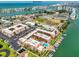 Aerial view of a waterfront community featuring tennis courts and a pool with boat docks in the background near the Gulf of Mexico at 8931 Blind Pass Rd # 262, St Pete Beach, FL 33706