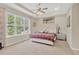 Bright main bedroom with a tray ceiling, a ceiling fan, and large window with trees outside at 9059 Spruce Creek Cir, Riverview, FL 33578