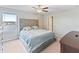 Comfortable main bedroom featuring a tufted headboard, ceiling fan and a large window overlooking the water at 9313 Lemon Drop Loop, Sun City Center, FL 33573