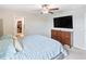 Main bedroom featuring a ceiling fan, dark wood dresser with large screen television, and walk-in closet at 9313 Lemon Drop Loop, Ruskin, FL 33573