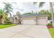 Attractive home exterior with lush lawn, concrete driveway leading to a three-car garage, and lovely landscaping at 10002 Colonnade Dr, Tampa, FL 33647