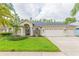 Beautiful exterior of a home featuring lush green lawn, mature palm trees, and a spacious three-car garage at 10002 Colonnade Dr, Tampa, FL 33647