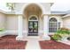 Elegant front entrance with double doors framed by columns and an arched entryway, complemented by lush landscaping at 10002 Colonnade Dr, Tampa, FL 33647