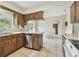 A kitchen with wood cabinets, tile flooring, and stainless steel dishwasher at 103 Hickory Creek Blvd, Brandon, FL 33511