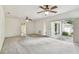 Large living room with multiple ceiling fans, neutral carpet, a sliding glass door, and a view into other rooms at 103 Hickory Creek Blvd, Brandon, FL 33511