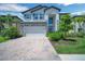 Beautiful home exterior featuring a two-car garage, brick driveway, and manicured landscaping at 10945 Sundrift Dr, Tampa, FL 33647
