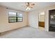 Cozy bedroom with neutral carpet, a ceiling fan, and natural light streaming in through a large window at 11305 Brown Bear Ln, Port Richey, FL 34668