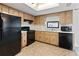 Functional kitchen featuring black appliances, wood cabinets, and white countertops at 11305 Brown Bear Ln, Port Richey, FL 34668