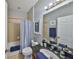 Bathroom with a granite vanity, blue towels, light fixtures, and a tub with light beige tile at 11408 Coventry Grove Cir, Lithia, FL 33547