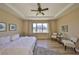 Comfortable bedroom features a tray ceiling, wood floors, a ceiling fan, and a sitting area by the window at 11408 Coventry Grove Cir, Lithia, FL 33547